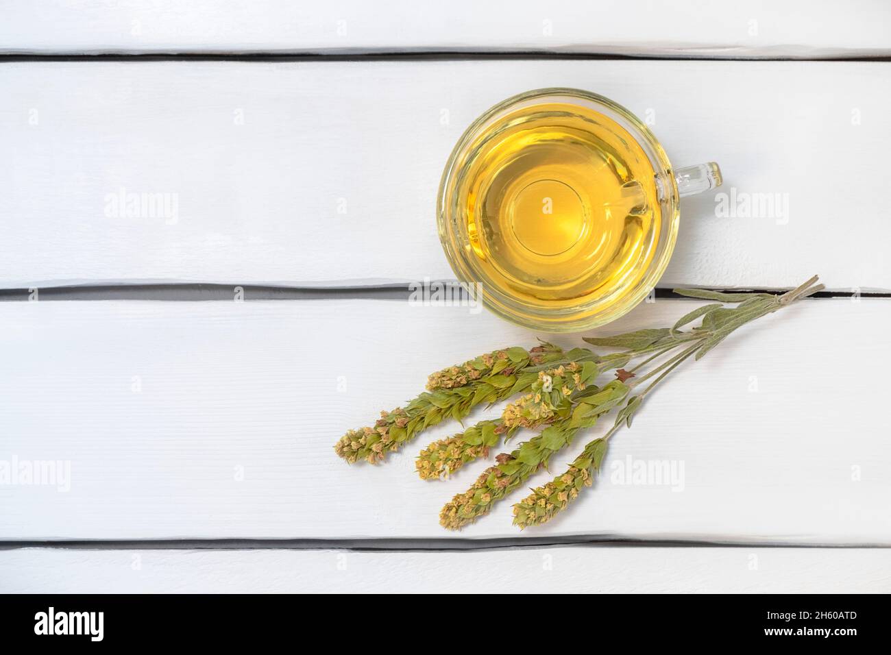Top view of glass cup of herbal tea Mursalski Chai with dried leaves and flowers on white wooden table, copy space Stock Photo