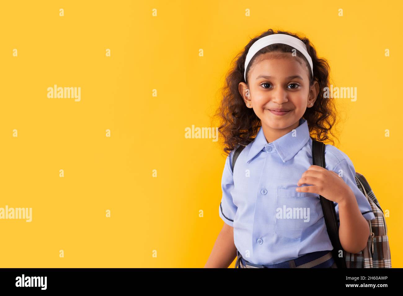 PORTRAIT OF A HAPPY GIRL IN SCHOOL UNIFORM LOOKING AT CAMERA Stock Photo