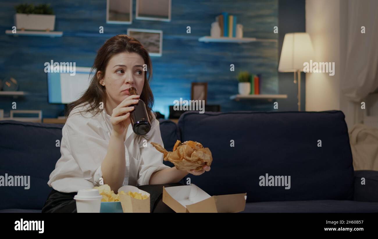 Young person enjoying takeaway burger and beer after work sitting at