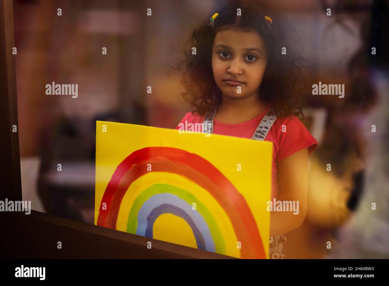 A girl in sad mood showing a rainbow painting in front of camera Stock Photo
