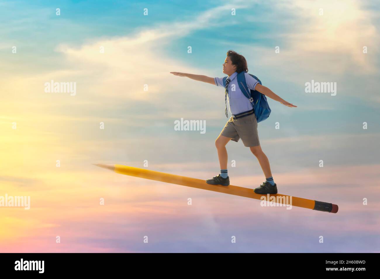 portrait of a boy in school uniform flying on pencil in the sky Stock ...