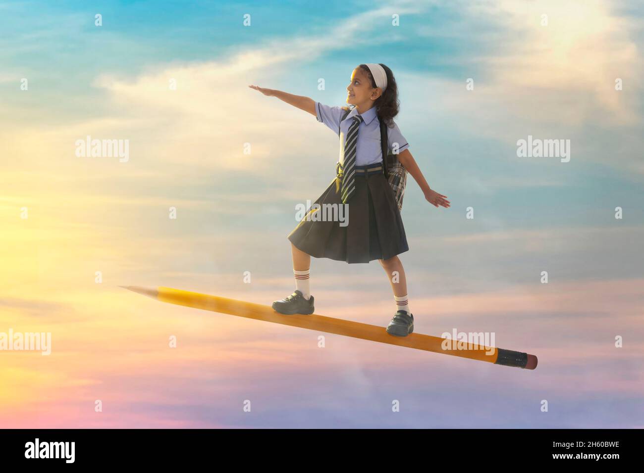 portrait of a girl in school uniform flying on pencil in the sky Stock ...