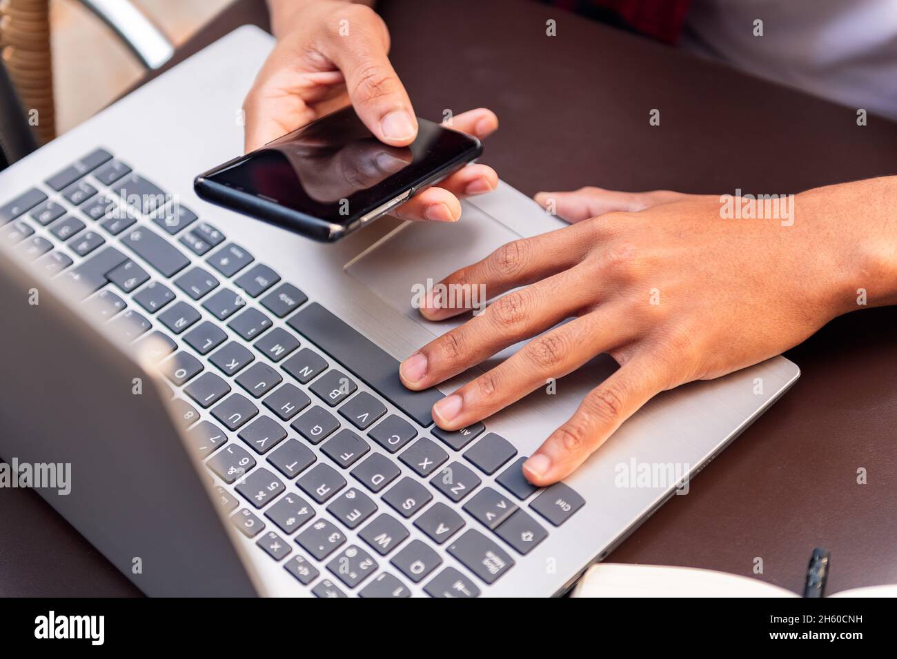 hands of an unrecognizable man working with his computer and phone ...