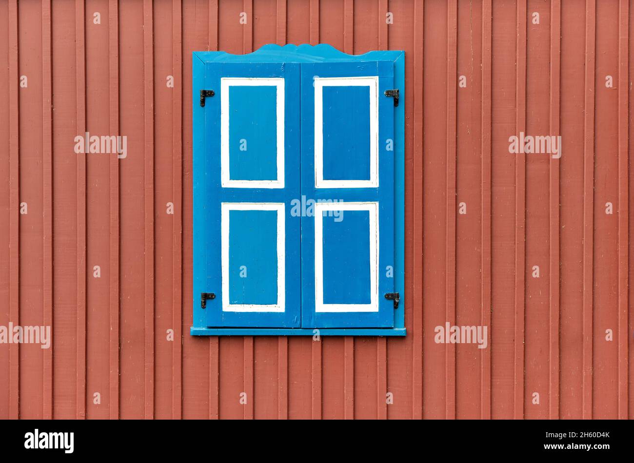 Colorful painted building wall with closed wooden shutters on  window, minimalist architecture background Stock Photo