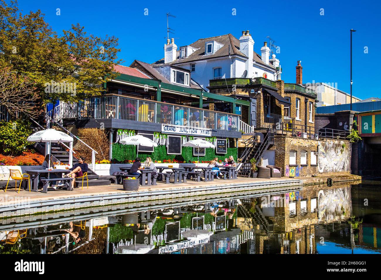 People having drinks outdoors by the Grand Union Canal at Grand Junction Arms pub, Harlesden, London, UK Stock Photo