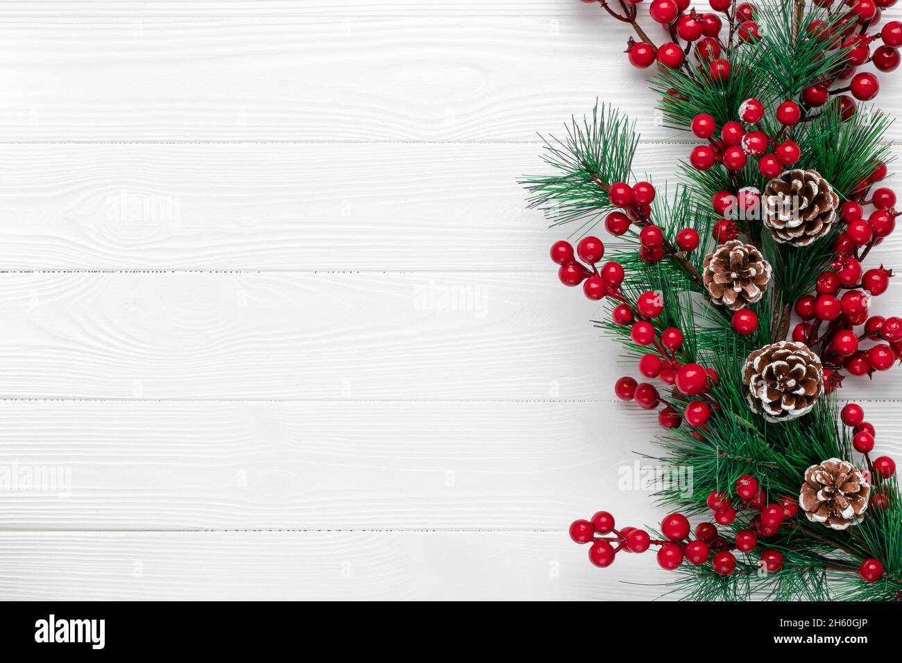 Christmas background with fir branches, cones and red holly berries ...