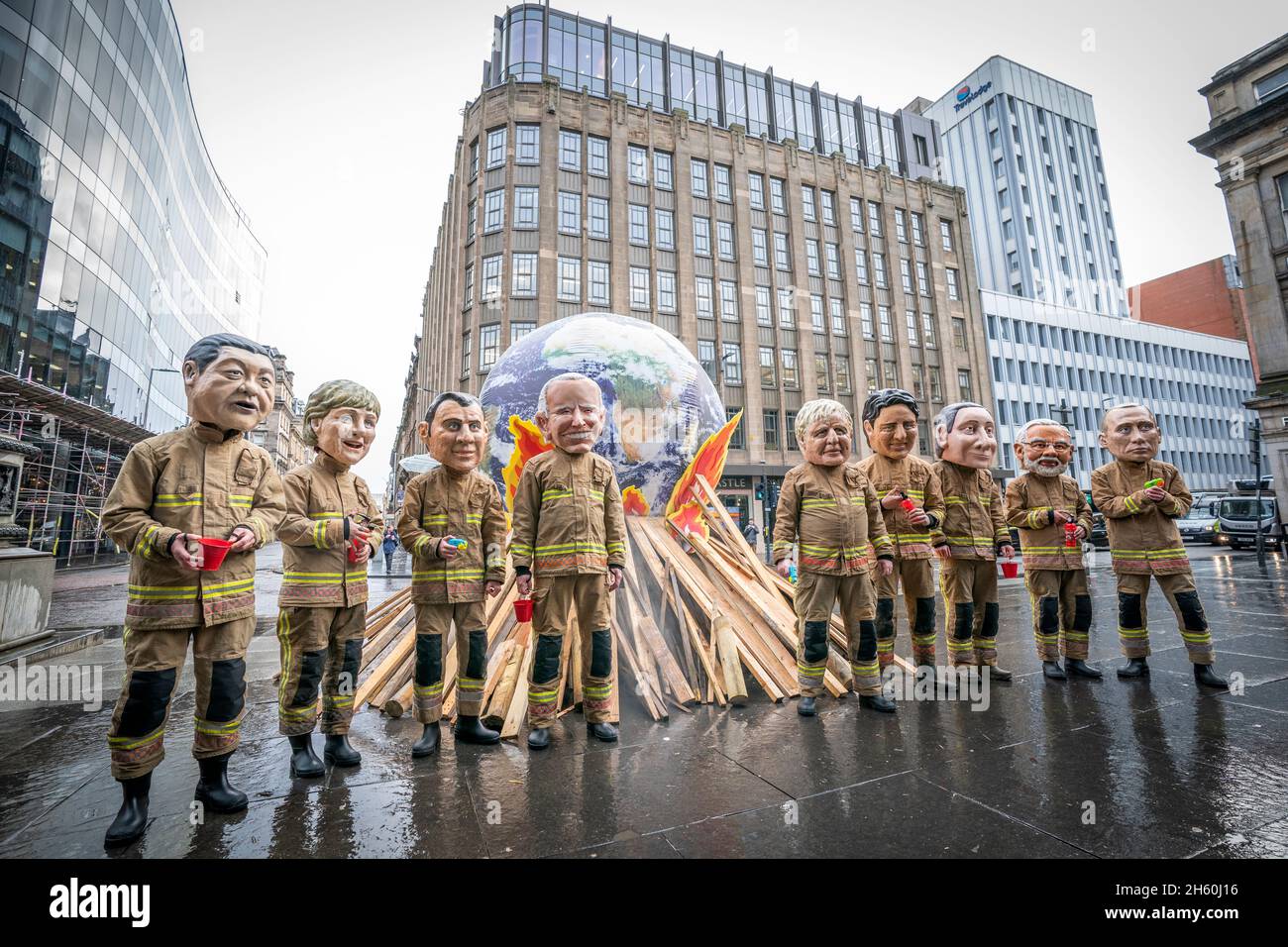 Campaigners wearing 'big heads' of world leaders, including Boris Johnson, Joe Biden, Justin Trudeau and Narendra Modi gather for Oxfam's 'Ineffective Fire-Fighting World Leaders' protest performance in front of a 10 foot globe with a simulated bonfire, during the official final day of the Cop26 summit in Glasgow. Picture date: Friday November 12, 2021. Stock Photo