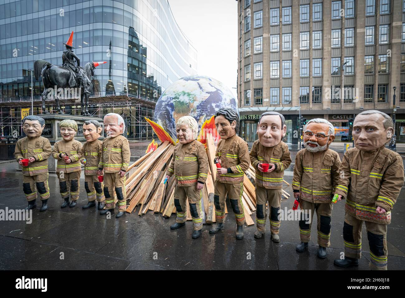 Campaigners wearing 'big heads' of world leaders, including Boris Johnson, Joe Biden, Justin Trudeau and Narendra Modi gather for Oxfam's 'Ineffective Fire-Fighting World Leaders' protest performance in front of a 10 foot globe with a simulated bonfire, during the official final day of the Cop26 summit in Glasgow. Picture date: Friday November 12, 2021. Stock Photo