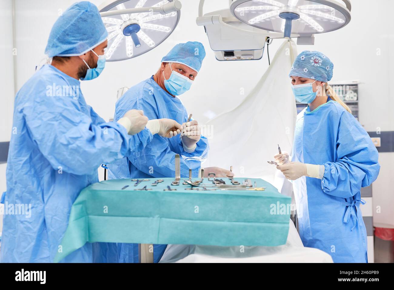 Resident physician and operating room nurse assist senior physician in the emergency operation in surgery Stock Photo