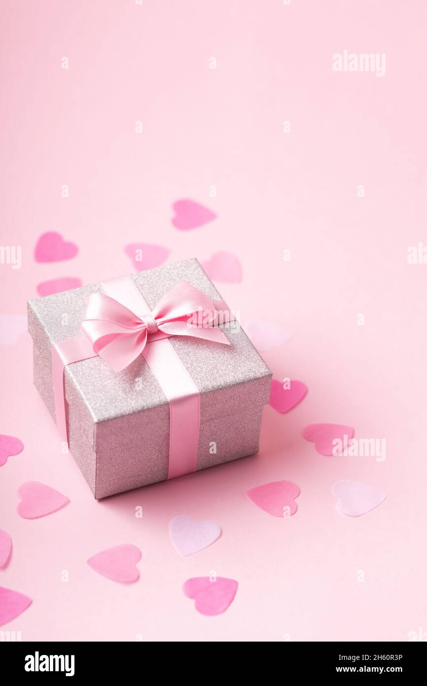Silver glitter gift box with pink ribbon bow on pink background with  confetti Stock Photo - Alamy