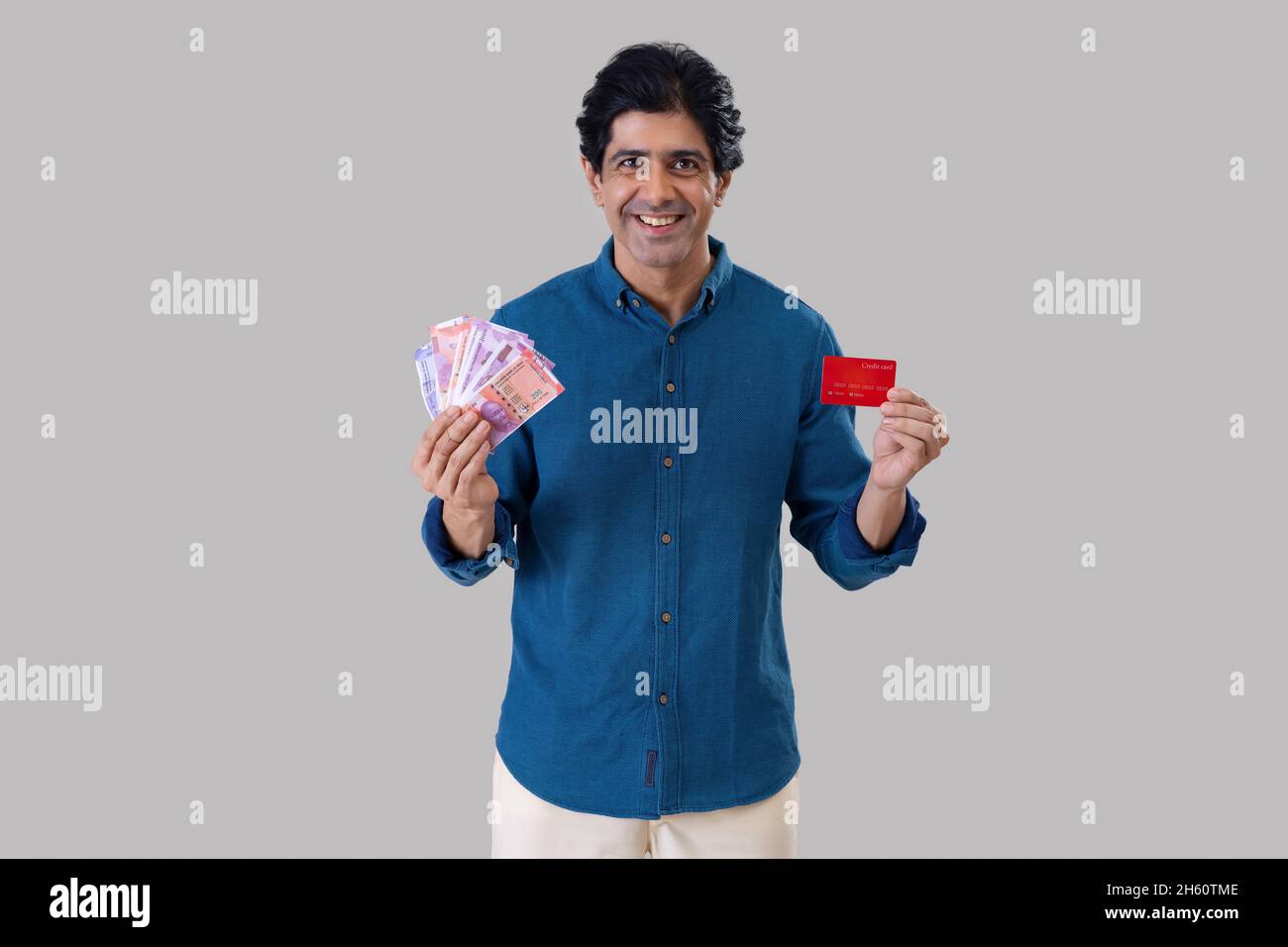 Indian man standing in front of camera with holding a credit card and ...