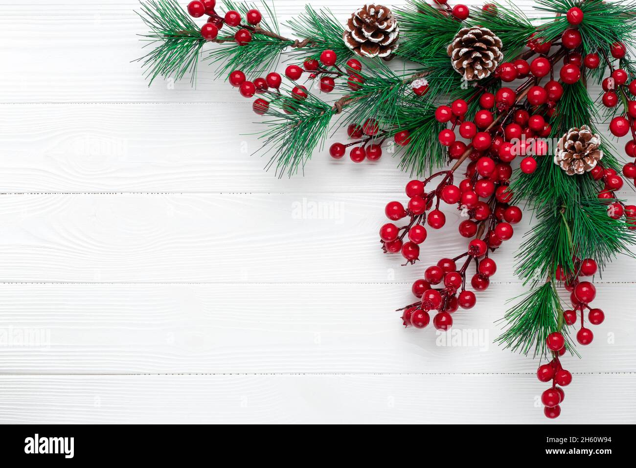 Christmas background with fir branches, cones and red holly berries. New year festive wreath of pine branches. Template, copy space. Empty place for t Stock Photo