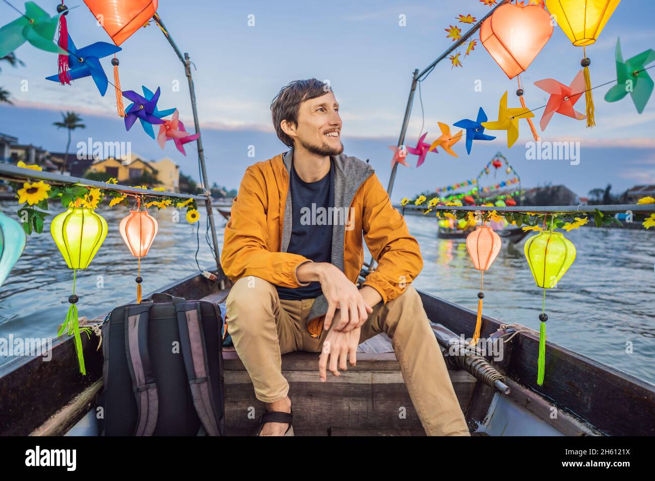 Happy man traveler ride a national boat on background of Hoi An ancient ...
