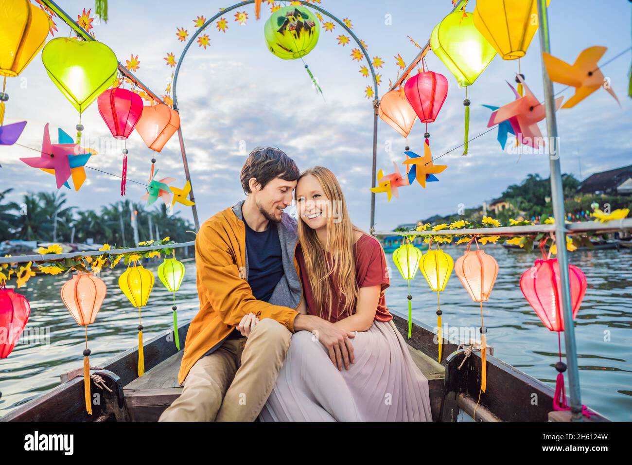 Happy couple of travelers ride a national boat on background of Hoi An ...