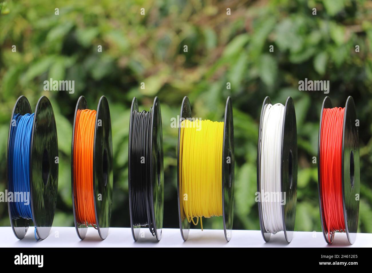 3D printer filaments on a spool isolated on a nature background show the concept of biodegradable plastic that is nature friendly Stock Photo