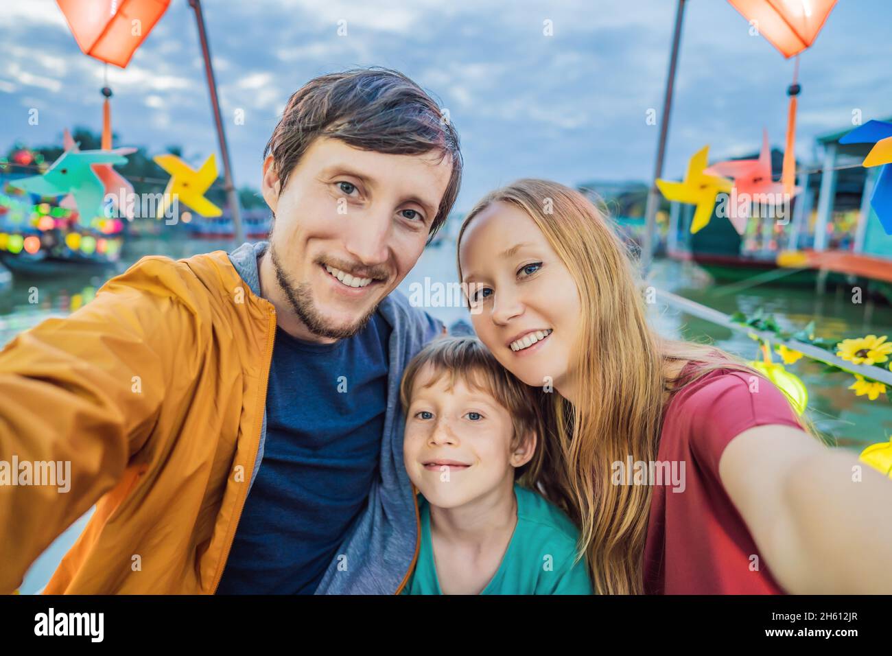 Happy family of travelers ride a national boat on background of Hoi An ...