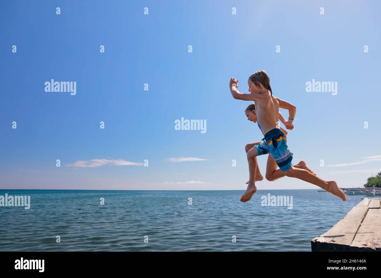 Young happy couple have fun at sea beach. Children run, jump high into water. Popular travel destination. Family summer vacation with kids at tropical Stock Photo