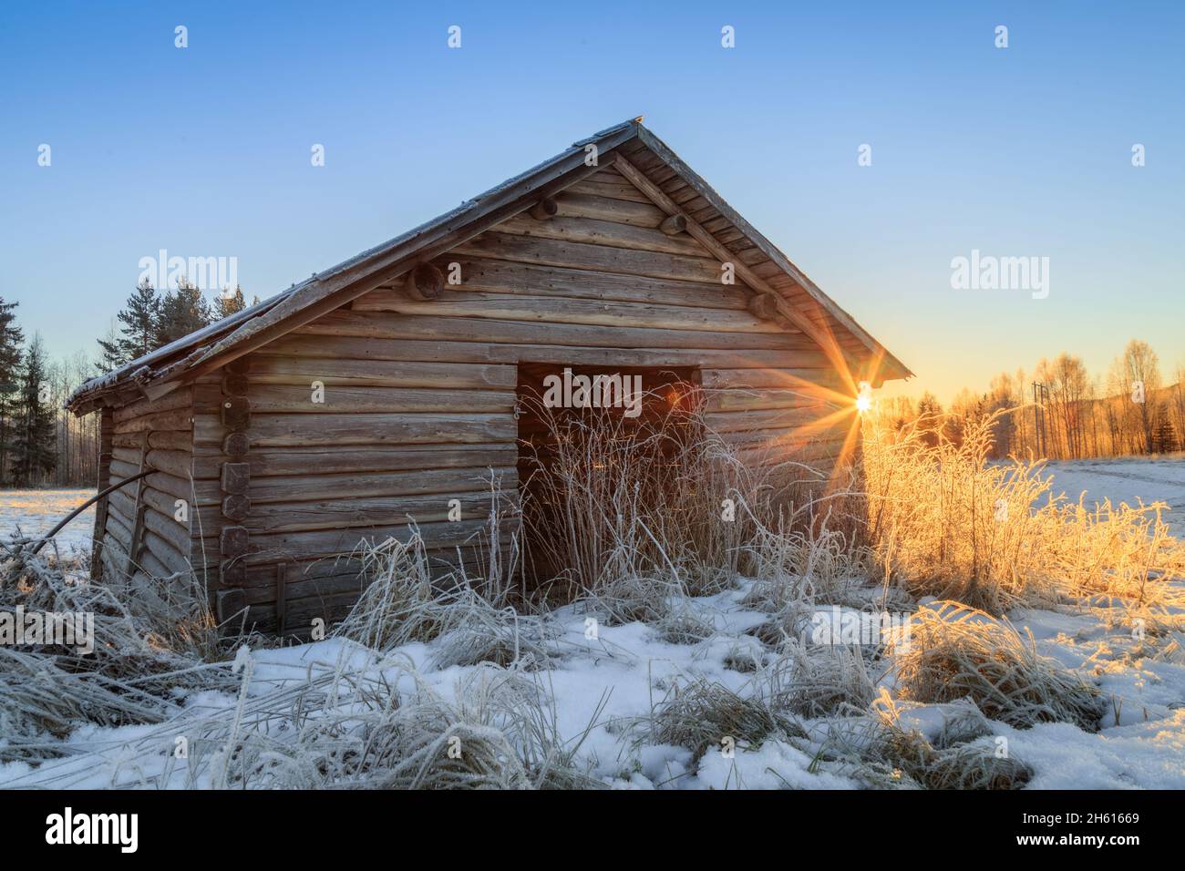 barn and snow during sunset with flares Stock Photo