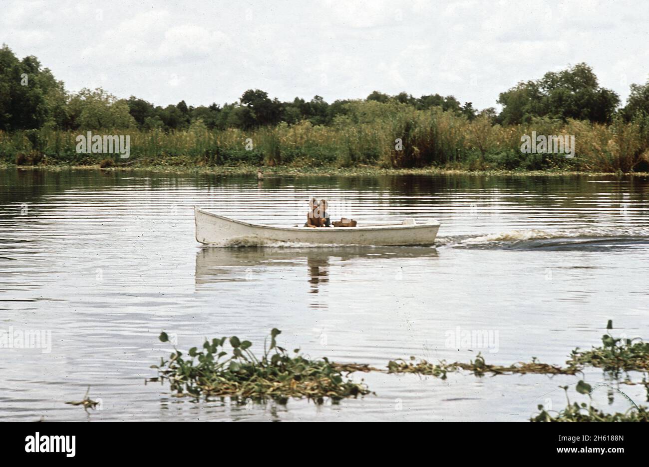 Two boys in a small boat fishing in Bayou Gauche, in the Louisiana wetlands ca. August 1972 Stock Photo