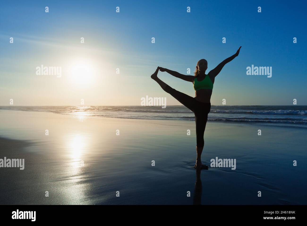 Black silhouette of active woman stretching at yoga retreat on sunset beach, sky with sun, ocean background. Travel lifestyle, people outdoor activity Stock Photo