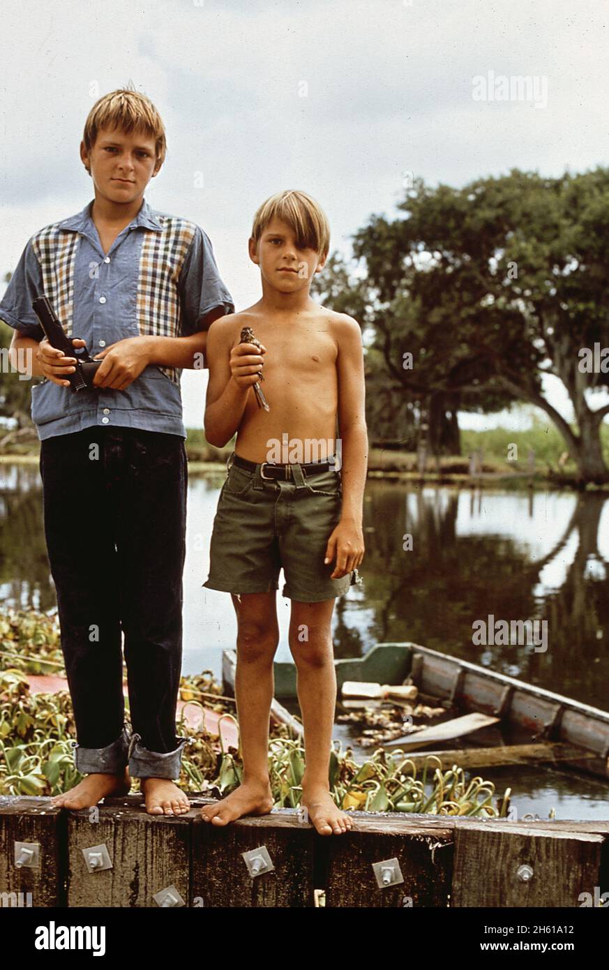 Boys with airgun and bird. These fishermen's sons live in Bayou Gauche, deep in the wetlands of Louisiana  ca. August 1972 Stock Photo