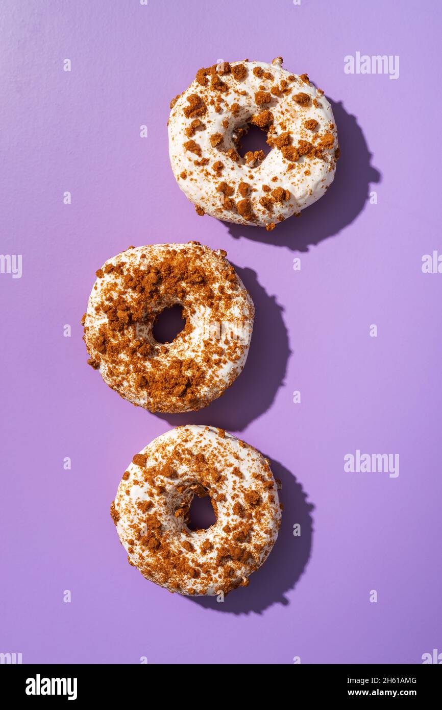 Sweet glazed donut with sprinkles on violet background. Top view Stock ...