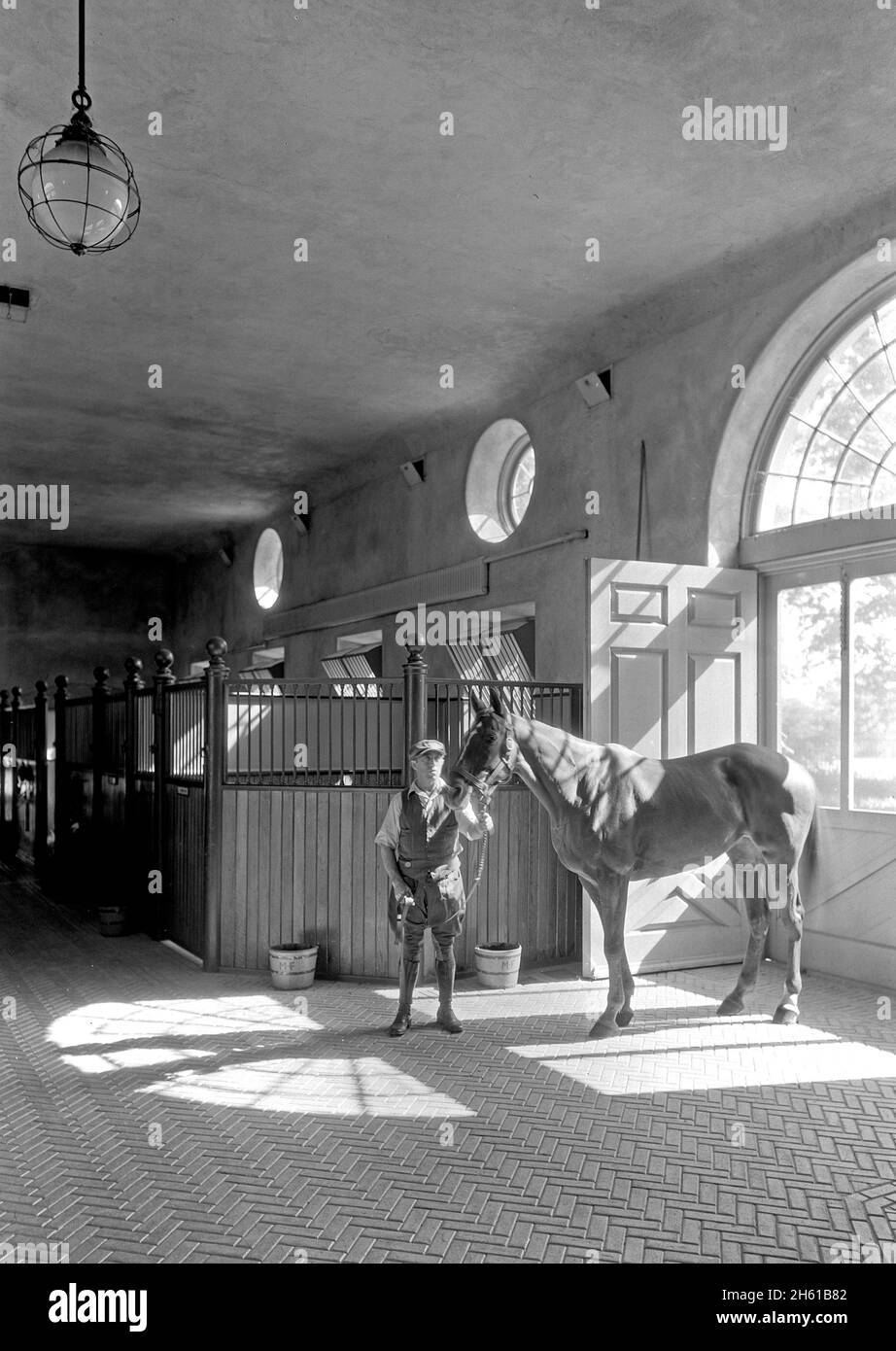 Man with a horse inside the stables at a luxury home in Huntington, L.I; 1933 Stock Photo