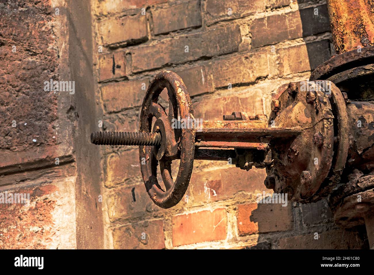 Old rusty gas control valve on the wall. An industrial valve in a large system. The gas transmission system of Ukraine is failing. Stock Photo