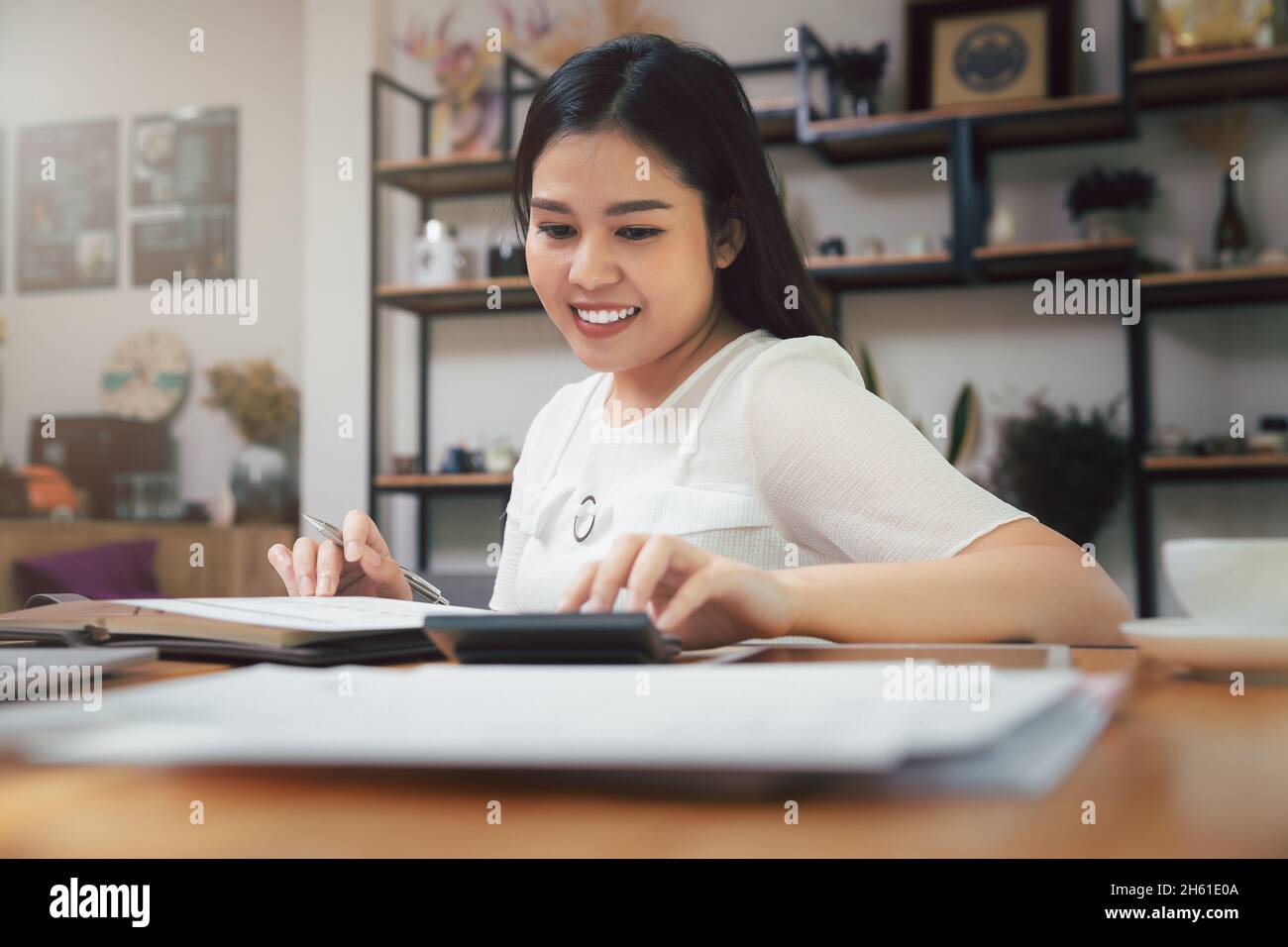 Young asian woman in smart casual wear working in home office. Social distance practice prevent coronavirus COVID-19. Stock Photo