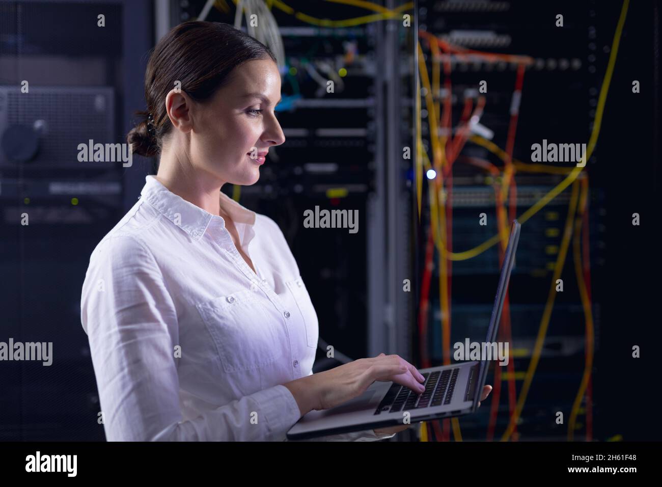 Caucasian female engineer using laptop in computer server room Stock Photo