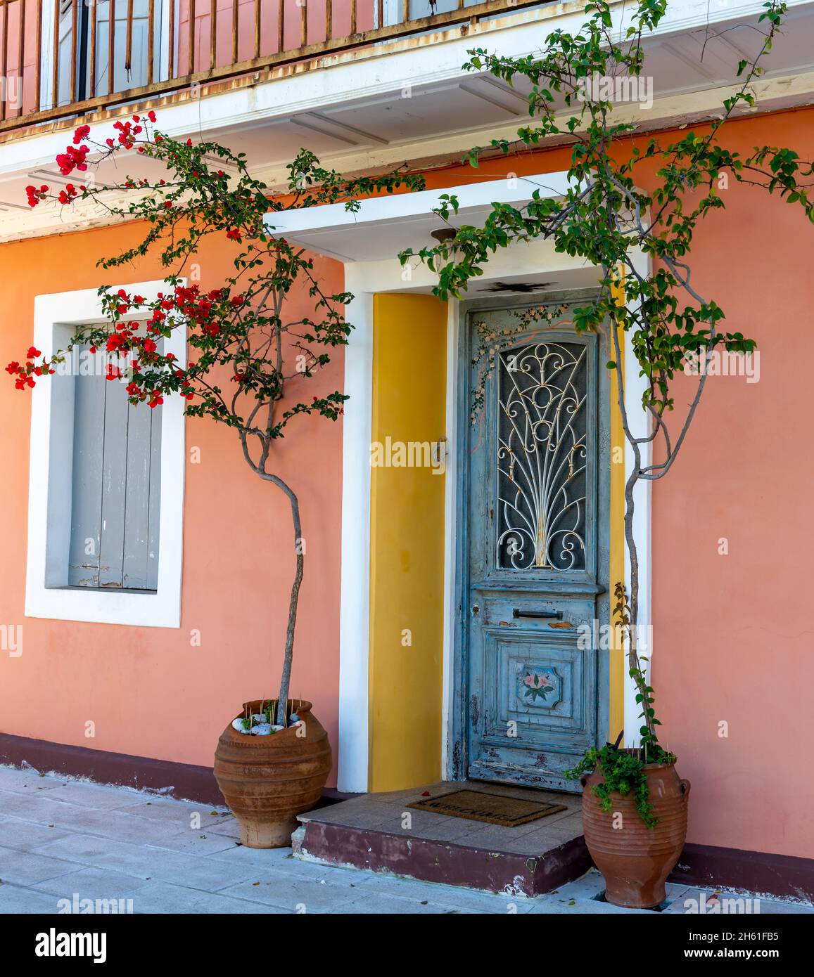 A colorful, beautiful Greek house front with a traditional door, windows and decorated with flowering plants. Stock Photo