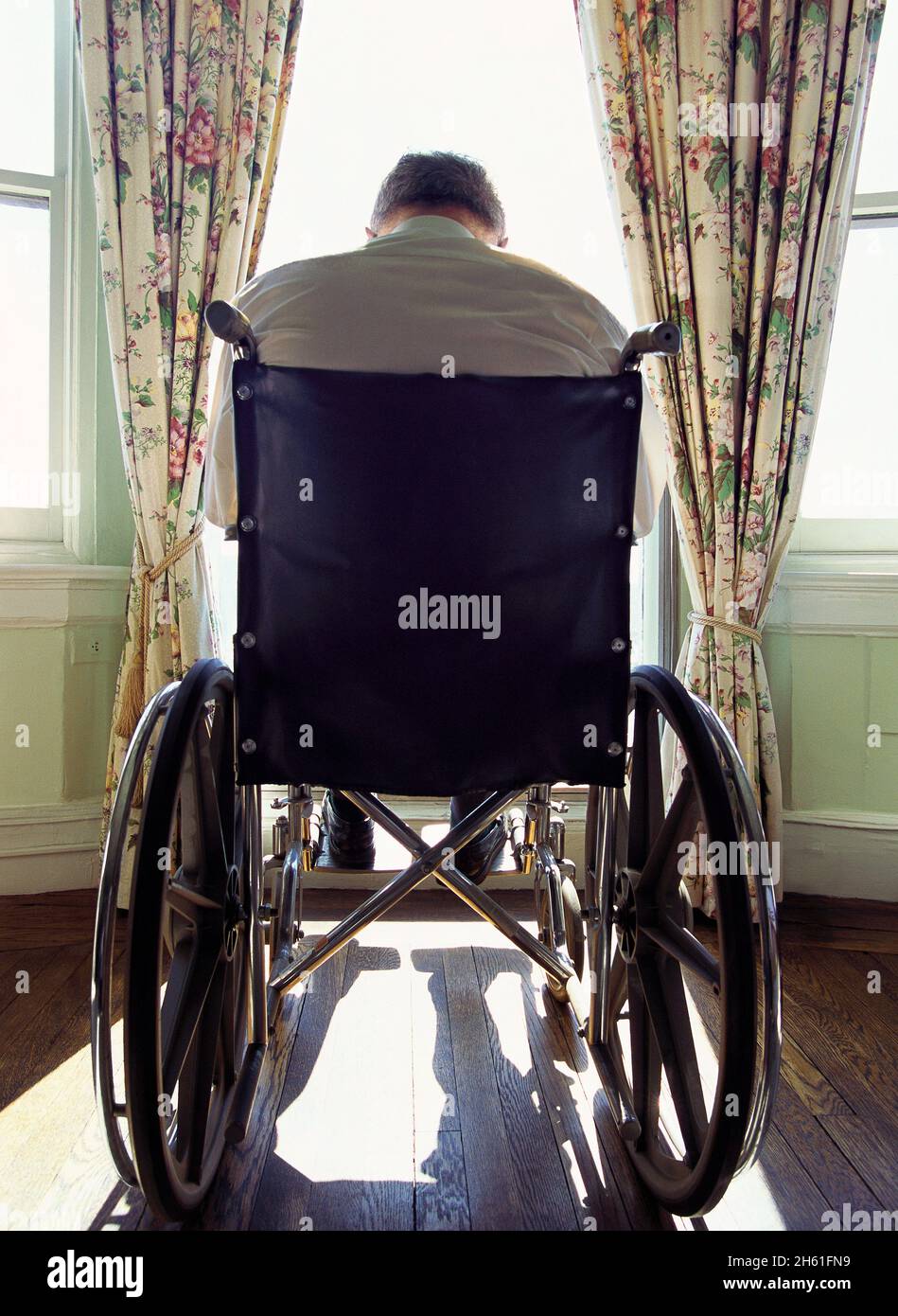 Elderly care. Man in wheelchair looking out window. Home health care care for the sick, disabled and ill. Loneliness in old age for handicapped Stock Photo