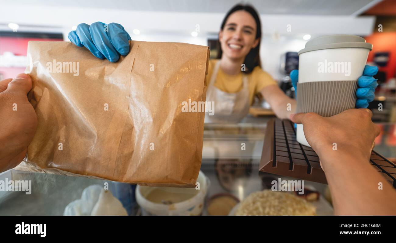 Female bar owner serving take away meal and coffee to clients Stock Photo