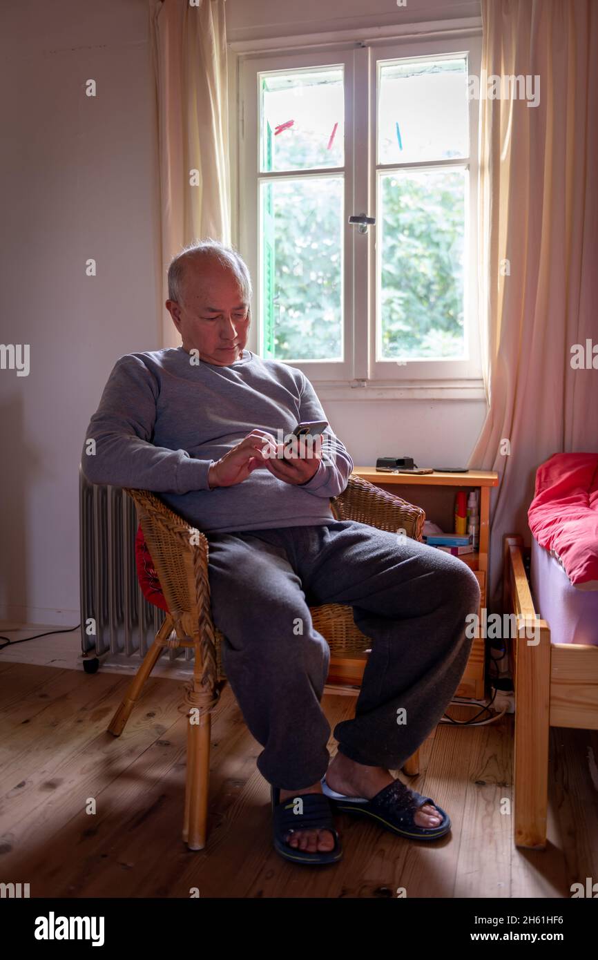 A matured man relaxing at home sitting on a comfortable chair by the window. Stock Photo