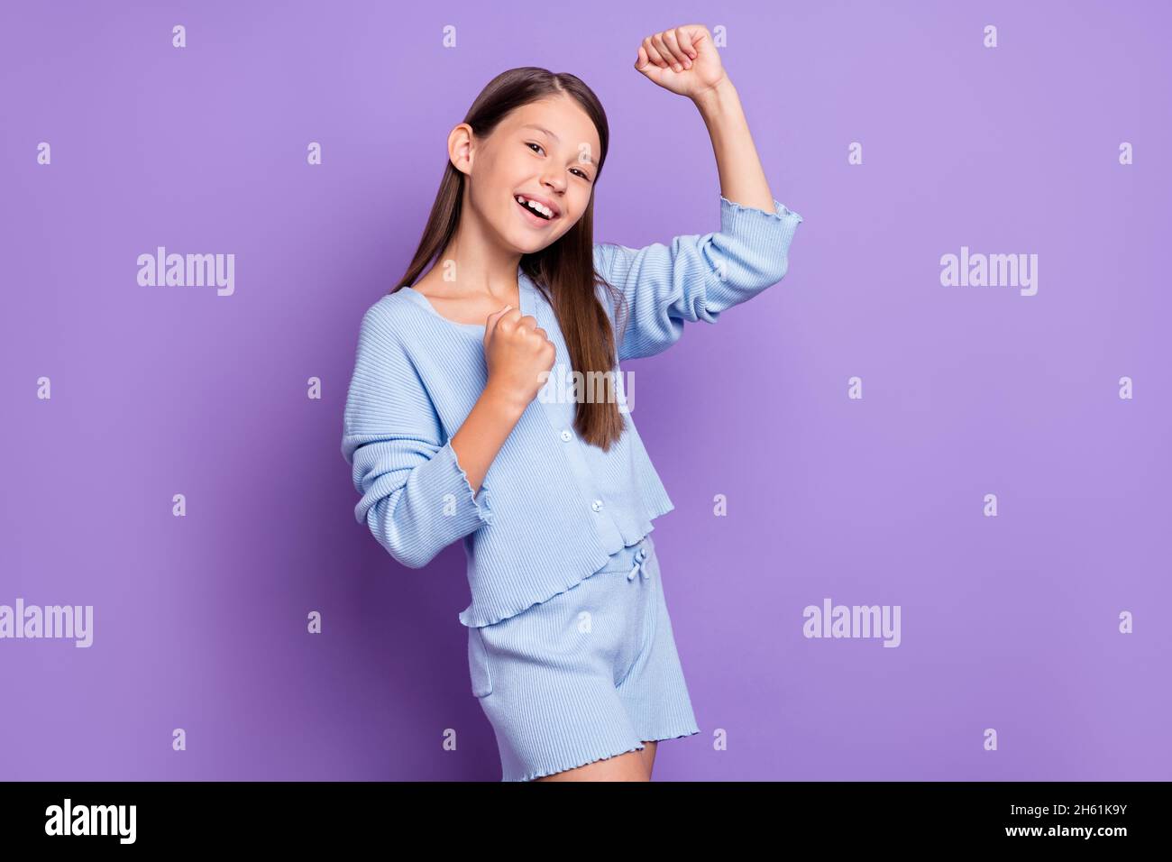 Photo of astonished brunette little girl hands fists wear blue shirt ...