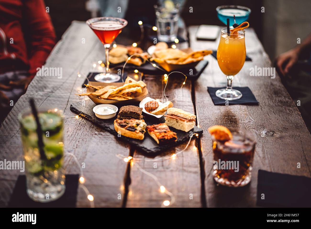 Blurred background of multicolored drinks and minimal food - Happy hour concept with fancy cocktails and tasty appetizers served at rooftop lounge Stock Photo