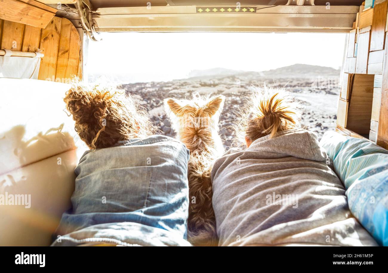 Hipster couple with cute dog traveling together on vintage van transport - Life inspiration concept with hippie people on minivan adventure trip Stock Photo