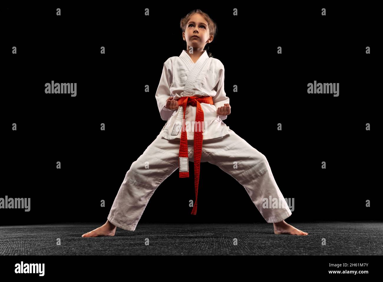 One little girl, young karate in fighting stance isolated over dark background. Concept of sport, education, skills Stock Photo
