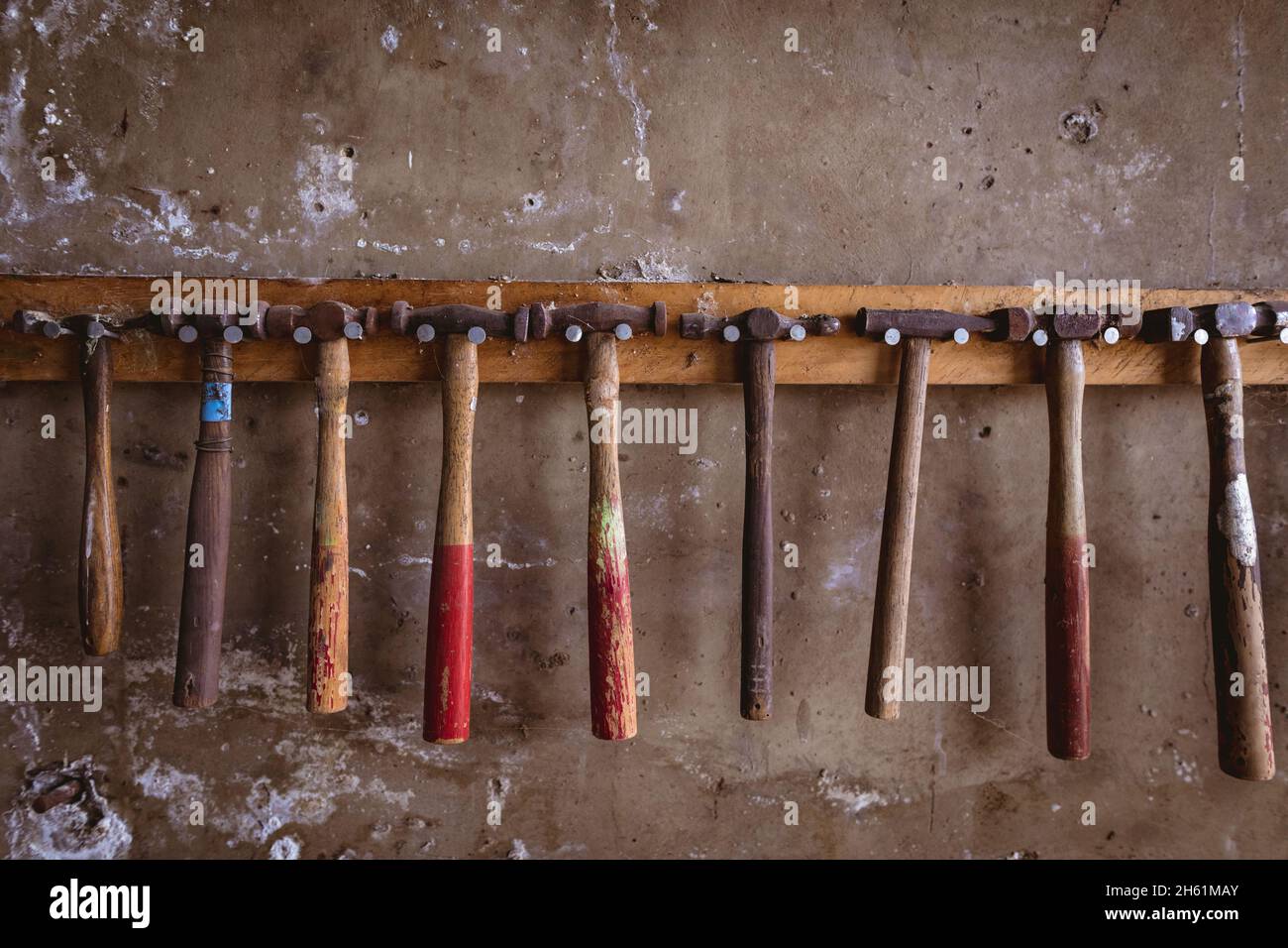 Various hammers hanging side by side on hook rack mounted on wall in industry Stock Photo