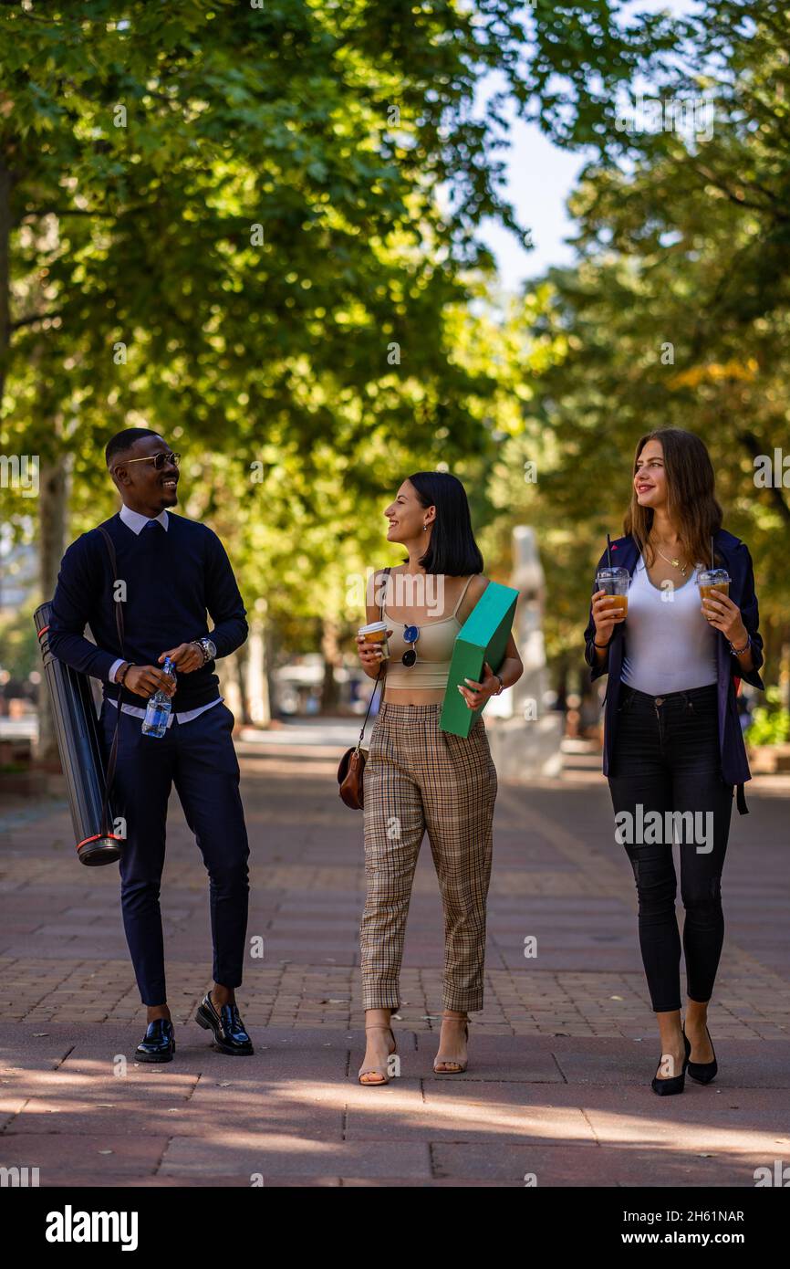 Three business people are talking and walking together while having a ...