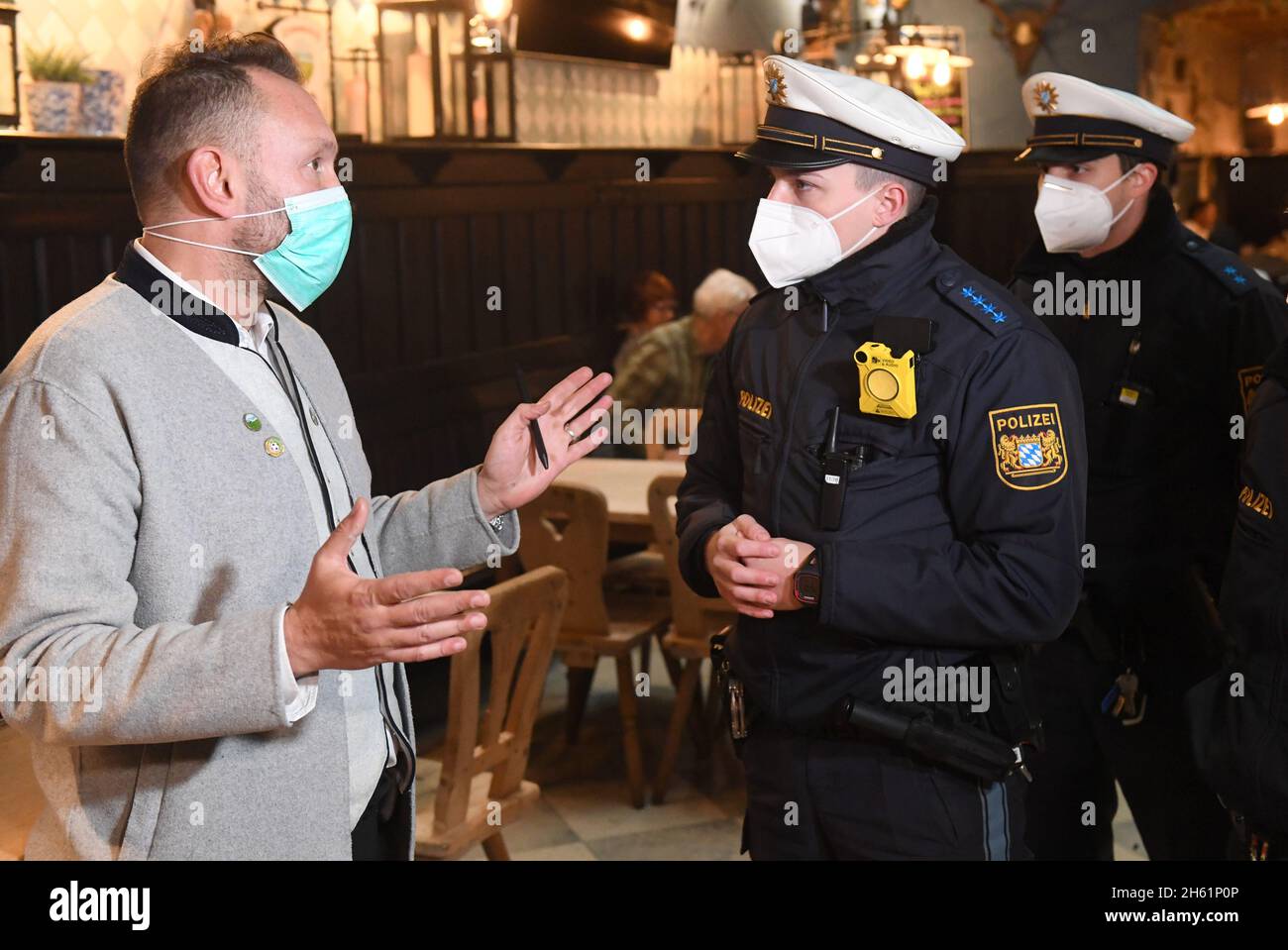 Munich, Germany. 12th Nov, 2021. Police officers talk to restaurant manager Bardis Jason (l) during a press event on Corona controls in Munich, Germany, to check compliance with Corona rules in front of the media. Credit: Felix Hörhager/dpa/Alamy Live News Stock Photo