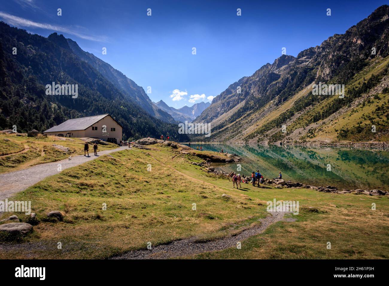 Hikers in the lake Gaube in Cauterets, the French Pyrenees. It is surrounded by the peaks Mayouret, Paloumeres and the Gaube. Stock Photo