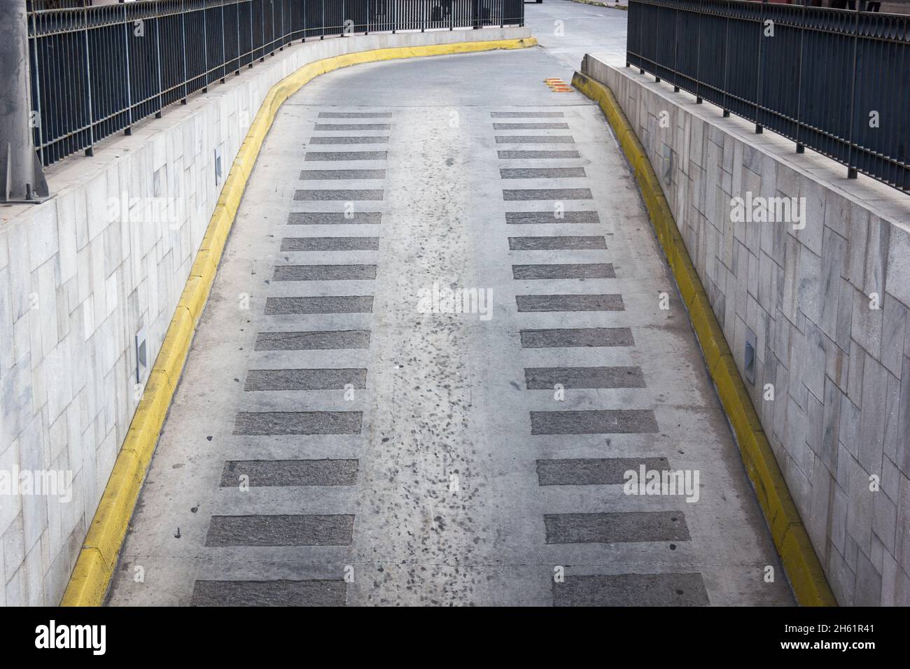 Grey pavement of garage ramp with yellow lines on the side. Parking entrance exit Stock Photo