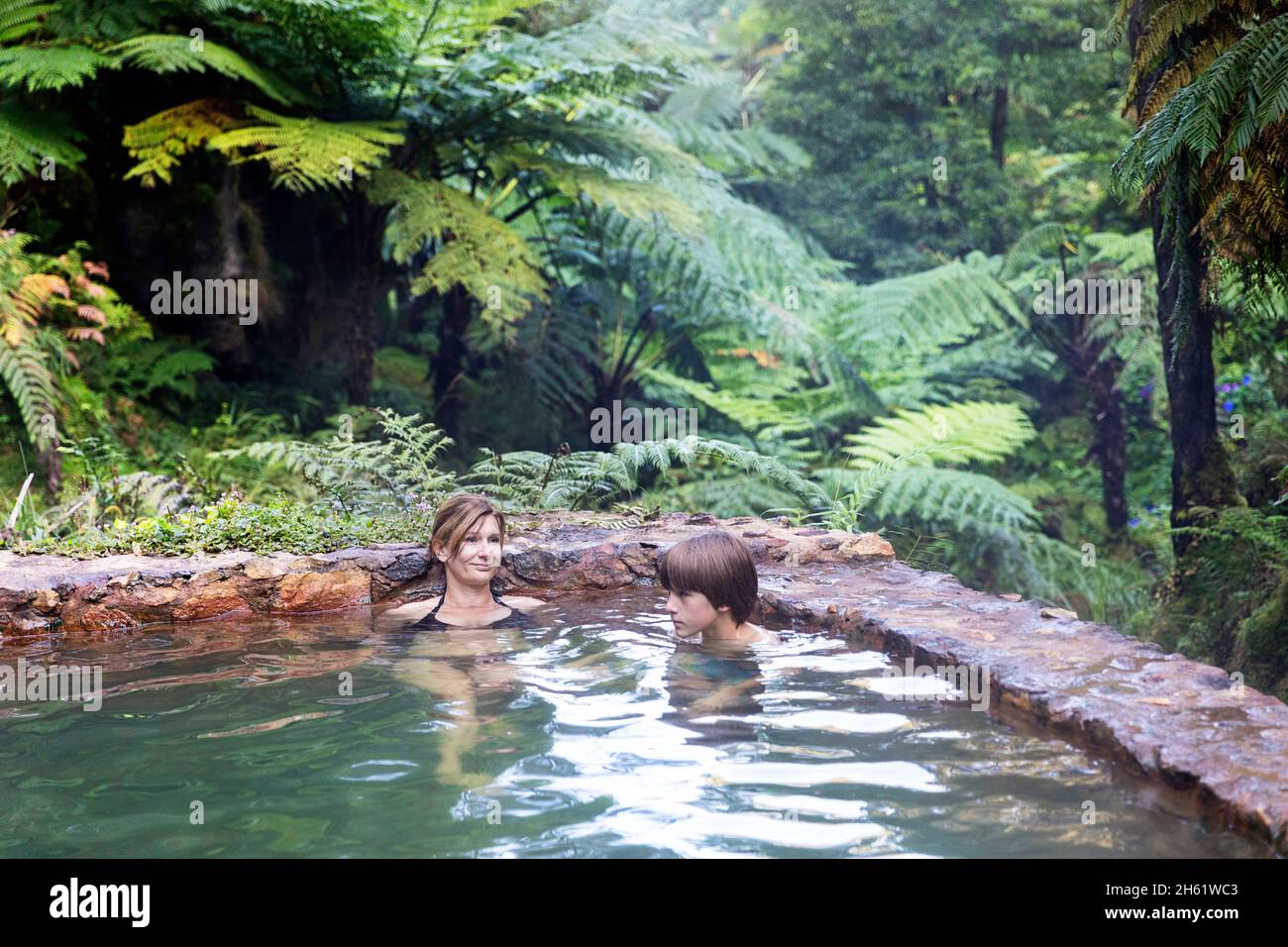 Mother and son bathing in the thermal pools of Caldeira Velha, Sao