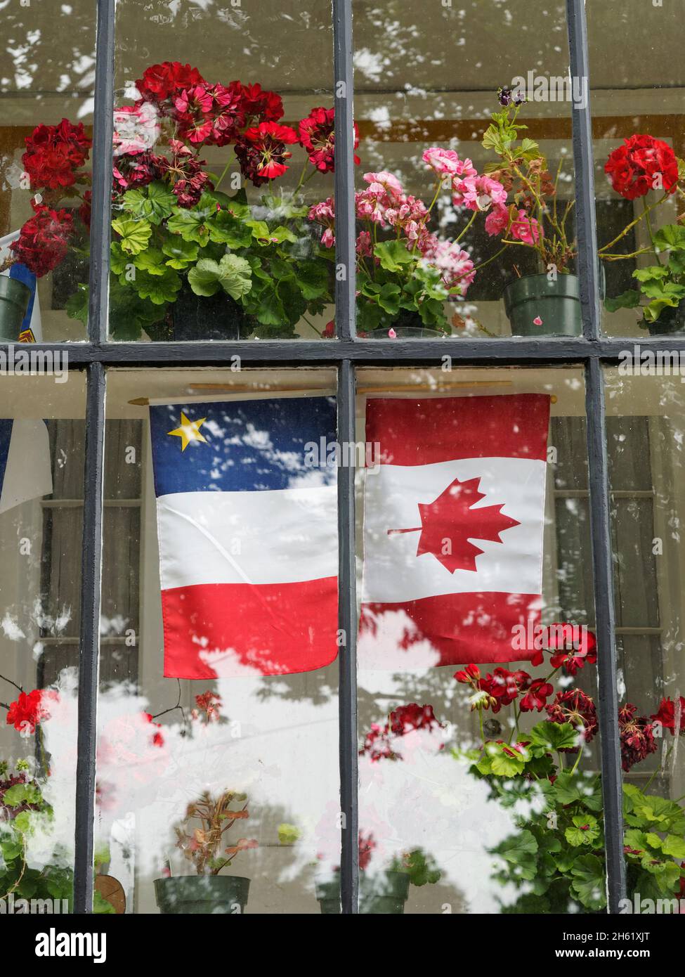 acadian and canadian flags in window,canada,francophone,french heritage,grand pré,nova scotia Stock Photo