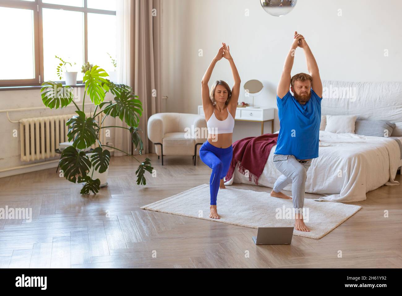 Middle-aged couple working out at home in front of a laptop monitor. Concept of a healthy lifestyle and maintaining oneself in shape after the age of Stock Photo