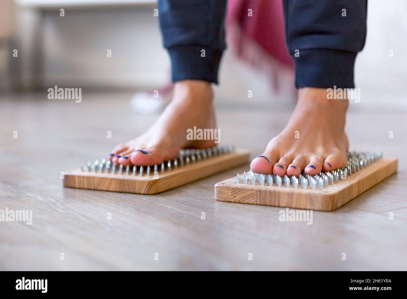 Photo of a female feet stand on a board with sharp nails over white background. Sadhu's board - practice yoga. Pain, trials, health, relaxation, cogni Stock Photo