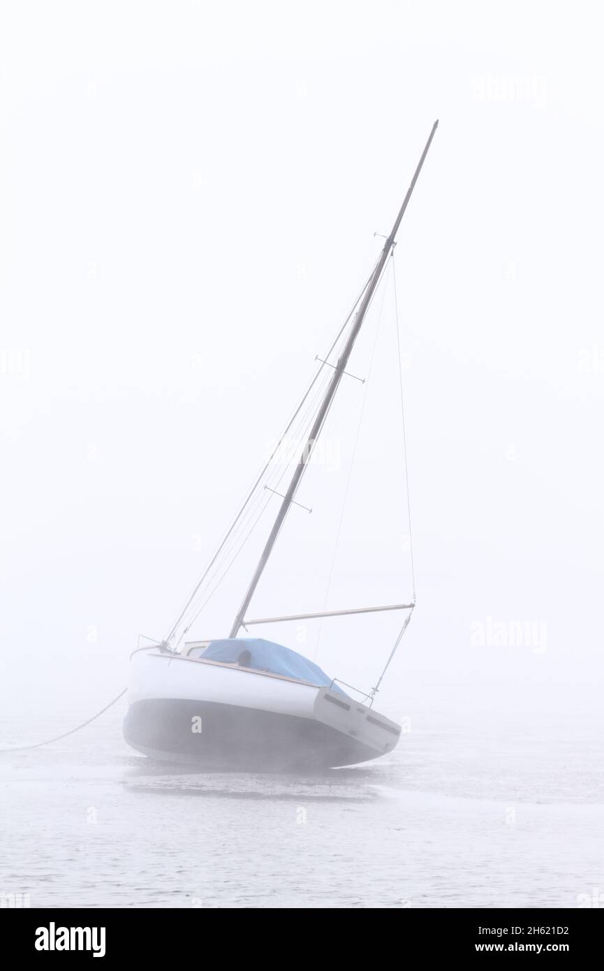 Sailing Boat, Yacht At Low Tide In Sea Fog At Christchurch Harbour UK Stock Photo