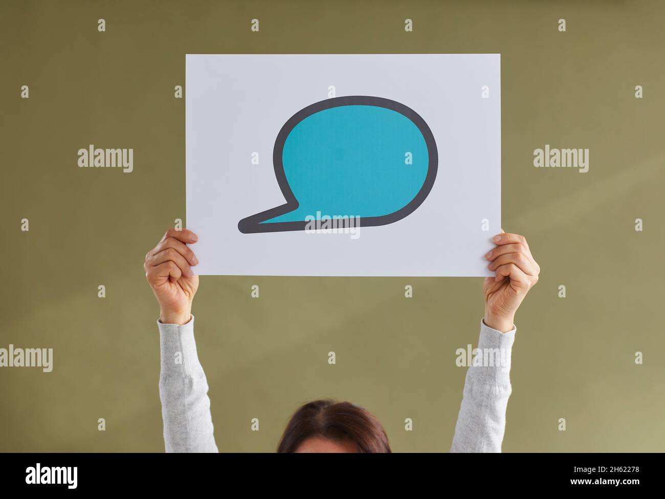 Woman holding up a blue blank mockup paper speech balloon or text ...