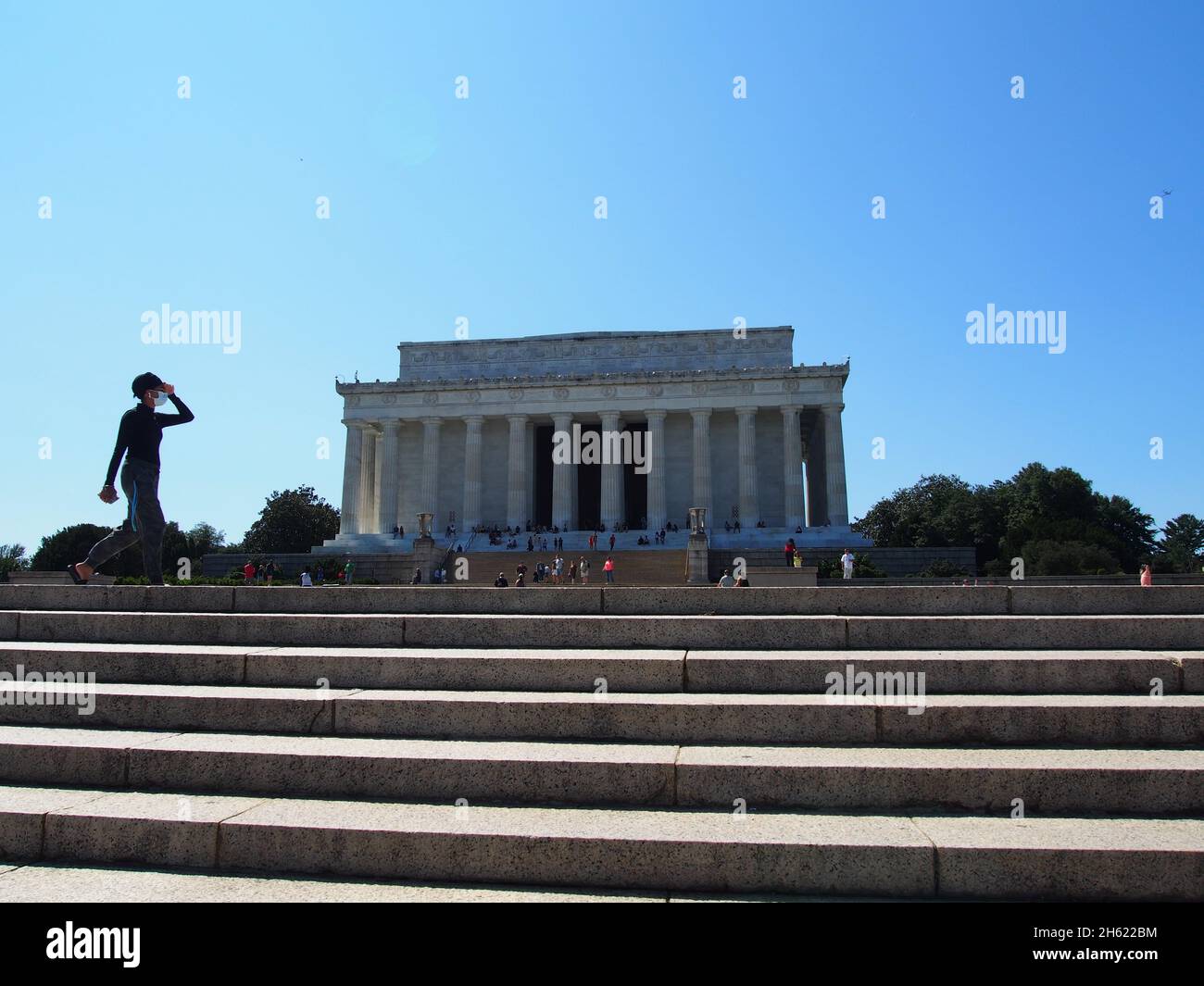 Masked woman exercise walking past the Lincoln Memorial in Washington, D.C., USA, 2021 © Katharine Andriotis Stock Photo